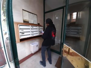 Distributeur en train de distribuer un cedex à l'entrée d'un immeuble dans le 7e arrondissement