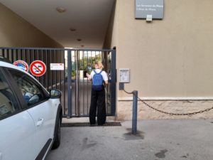 hôtesse utilisant son Badge VIGIK devant une grille d'une résidence proche des Catalans