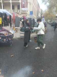 hôtesse donnant un flyers à une passante sur le marché 