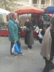 hôtesse donnant un flyers à un passant sur le marché 